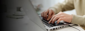 Hands typing on a laptop keyboard in a modern workspace, representing digital experience management, user interaction, and everyday technology use.