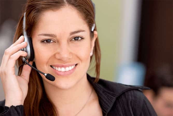 Customer support representative wearing a headset, smiling while assisting customers in a professional service environment.